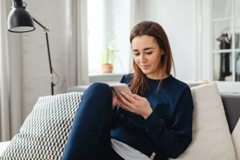 Woman sitting on a sofa looking at her smartphone.