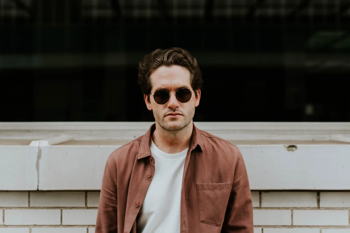 Man in sunglasses posing in front of a striped wall.