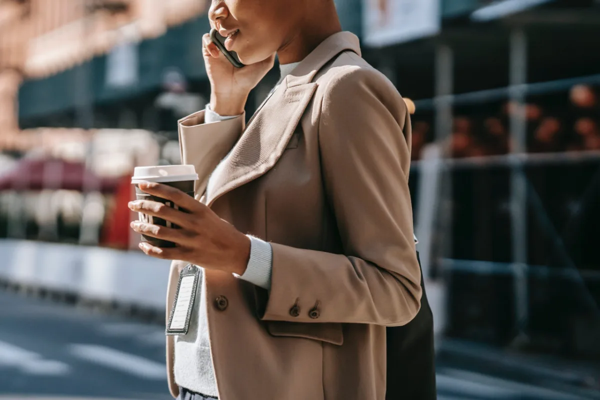 Businesswoman talking on the phone while holding a coffee cup on a city street.