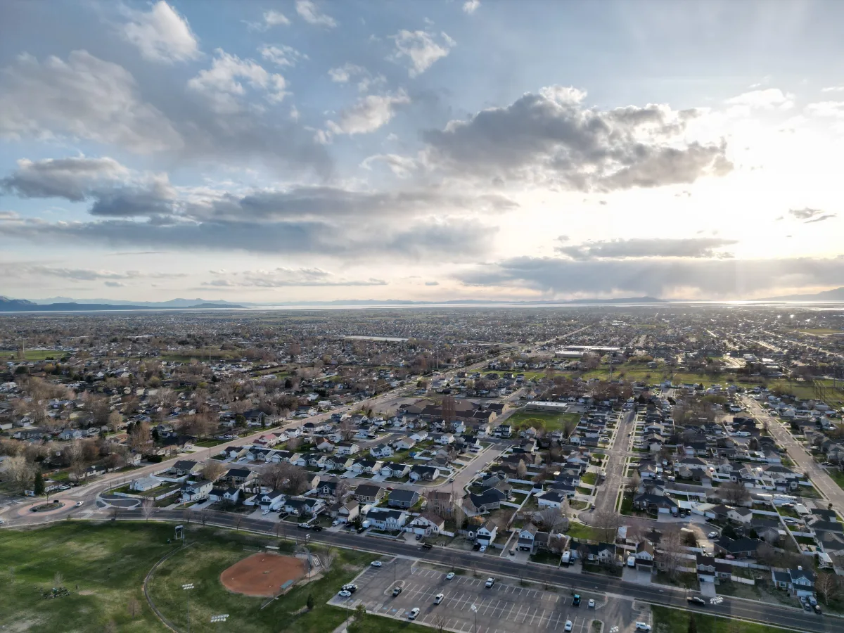 Aerial view of a suburban area at sunset with clouds casting shadows over the landscape.