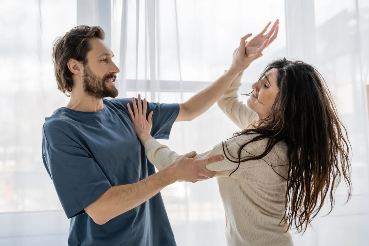 Two people practicing partner dance moves indoors.