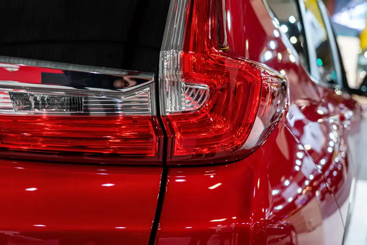 The tail lights of a red car driven by a driver at an auto show.