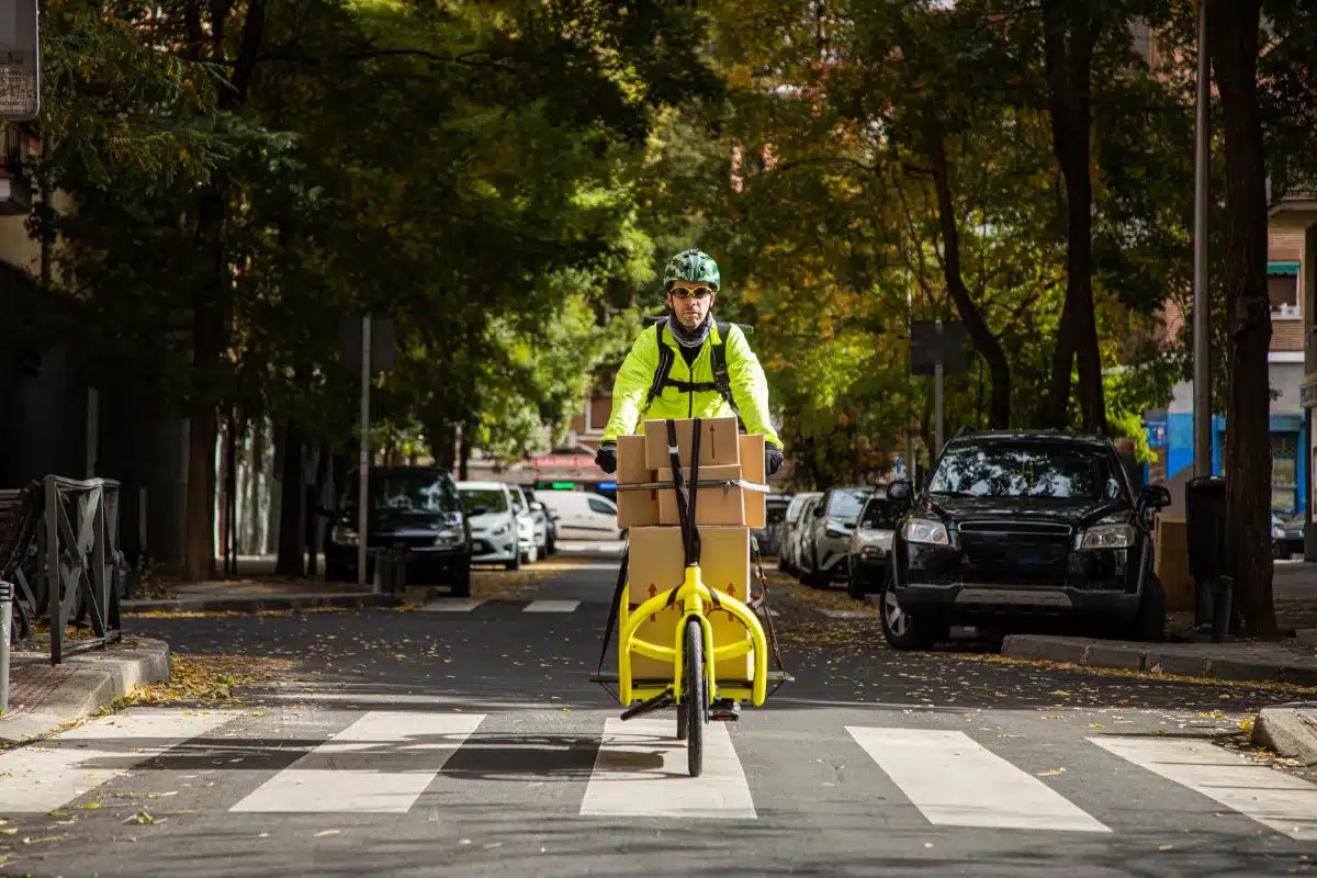 A man riding a yellow bicycle with a yellow box on it during his probation.