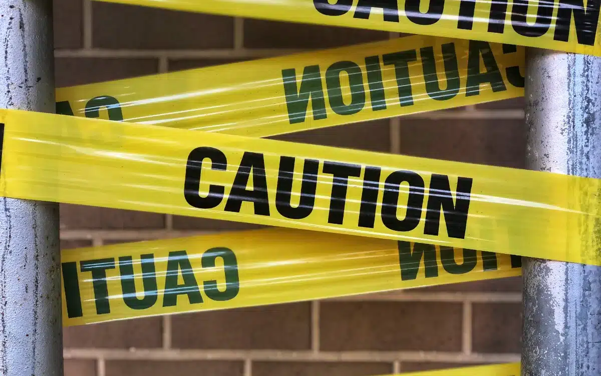 Caution tape wrapped around a metal pole in a restricted area, indicating a possible misdemeanor violation.