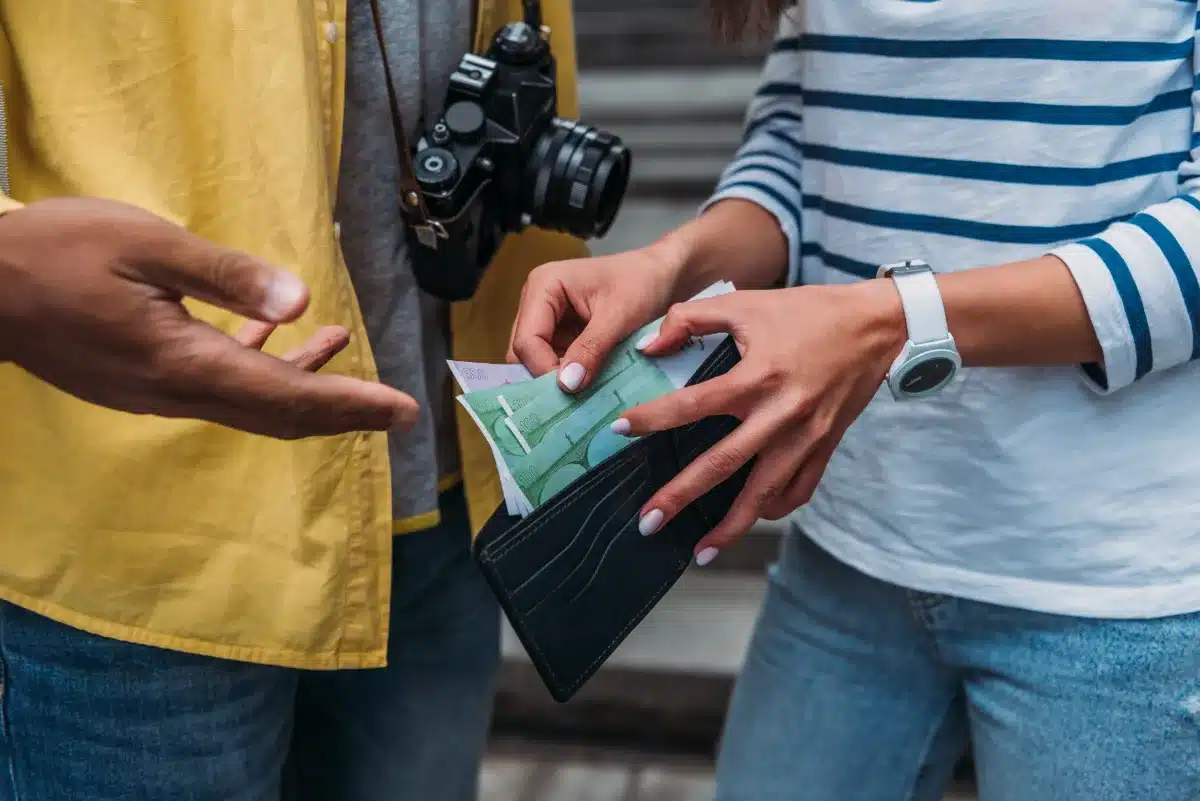 A man is holding a wallet whilst a woman is looking at it.