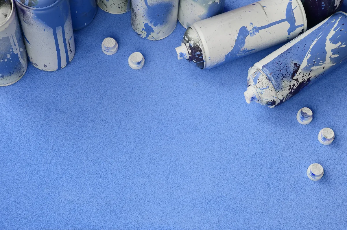 Several blue spray paint cans neatly arranged on a vibrant blue surface.