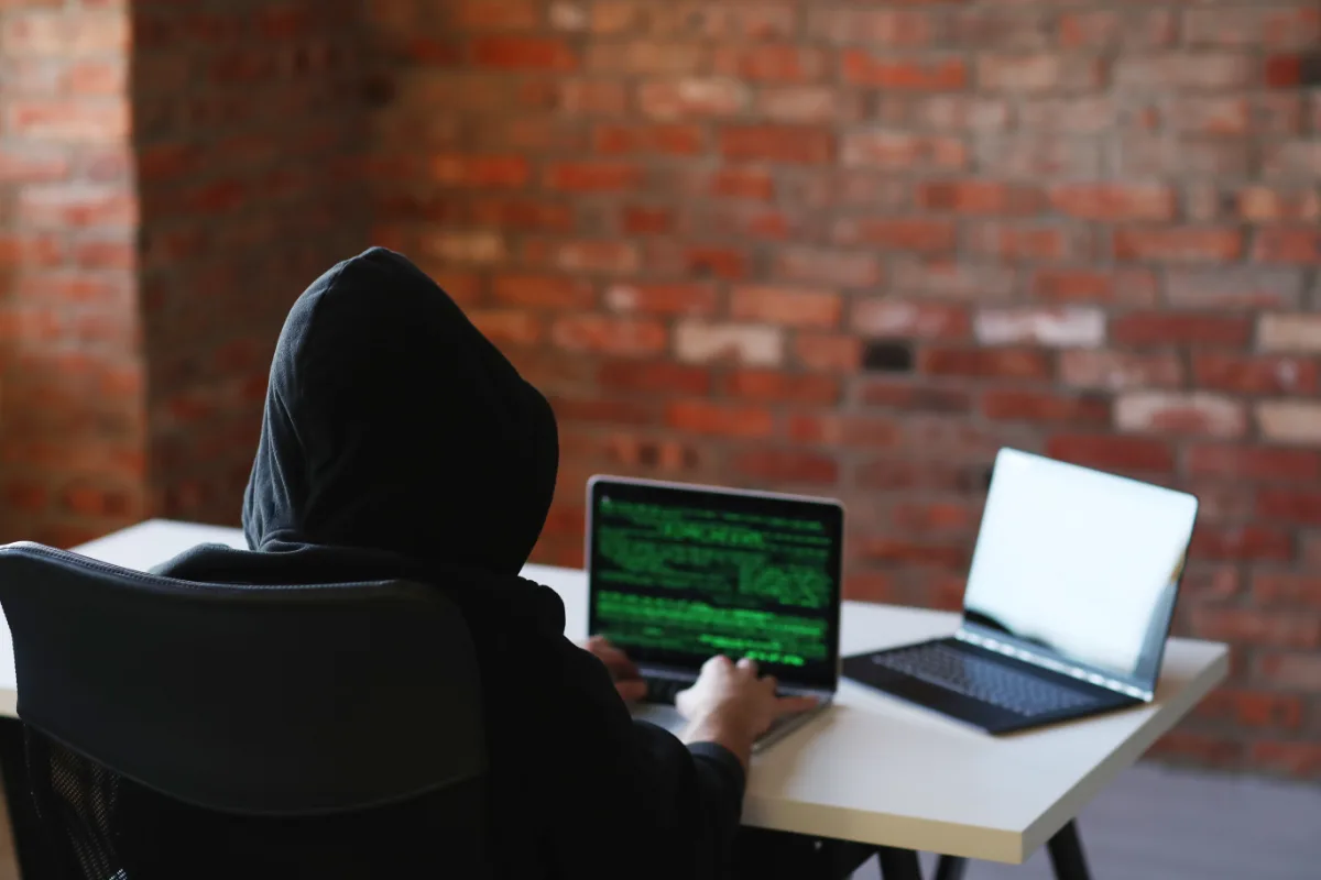 A man in a hoodie sitting at a desk with a laptop, possibly addressing probation or charges related to a misdemeanor.
