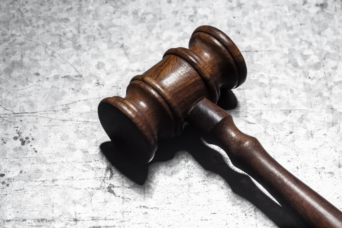 A wooden gavel striking a metal surface in a courtroom, emphasizing the role of a lawyer in addressing misdemeanors.