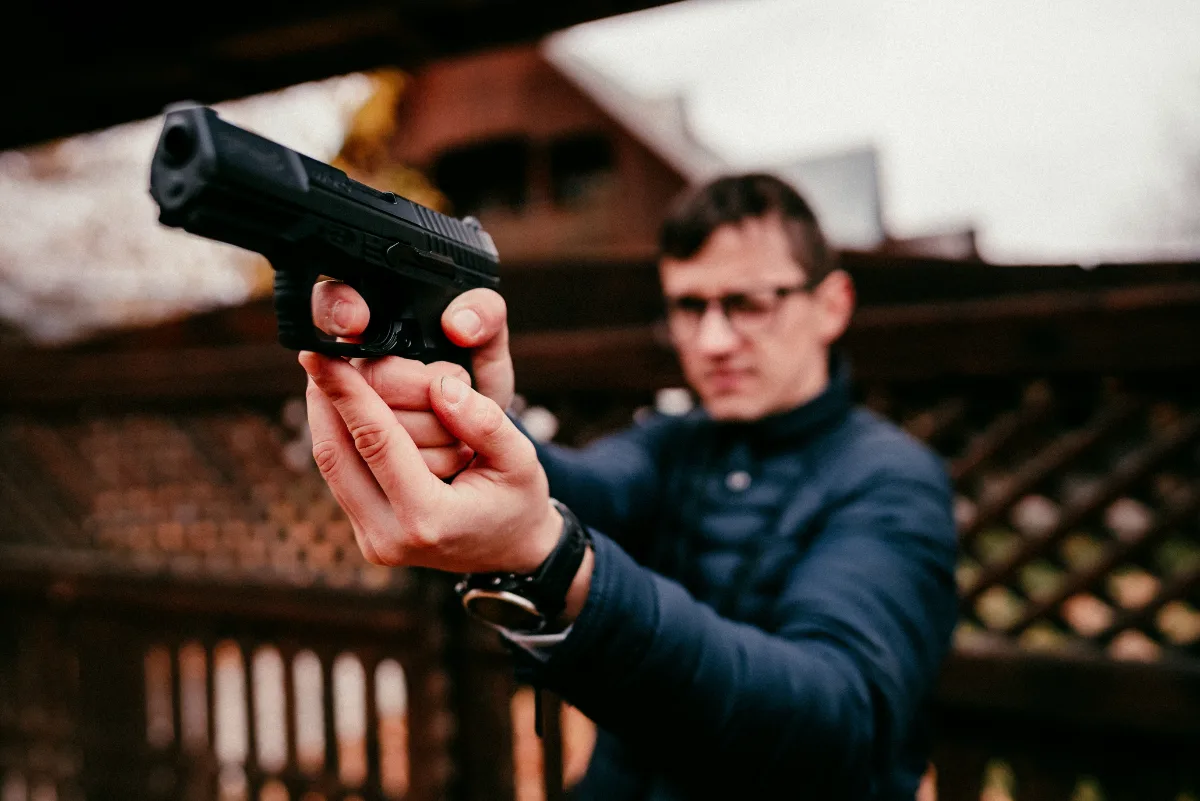 Man holding a handgun in focus with a blurred background.