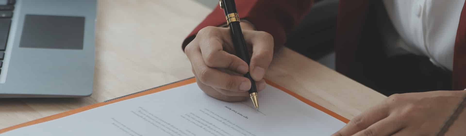 A person signing a document with a pen on probation.