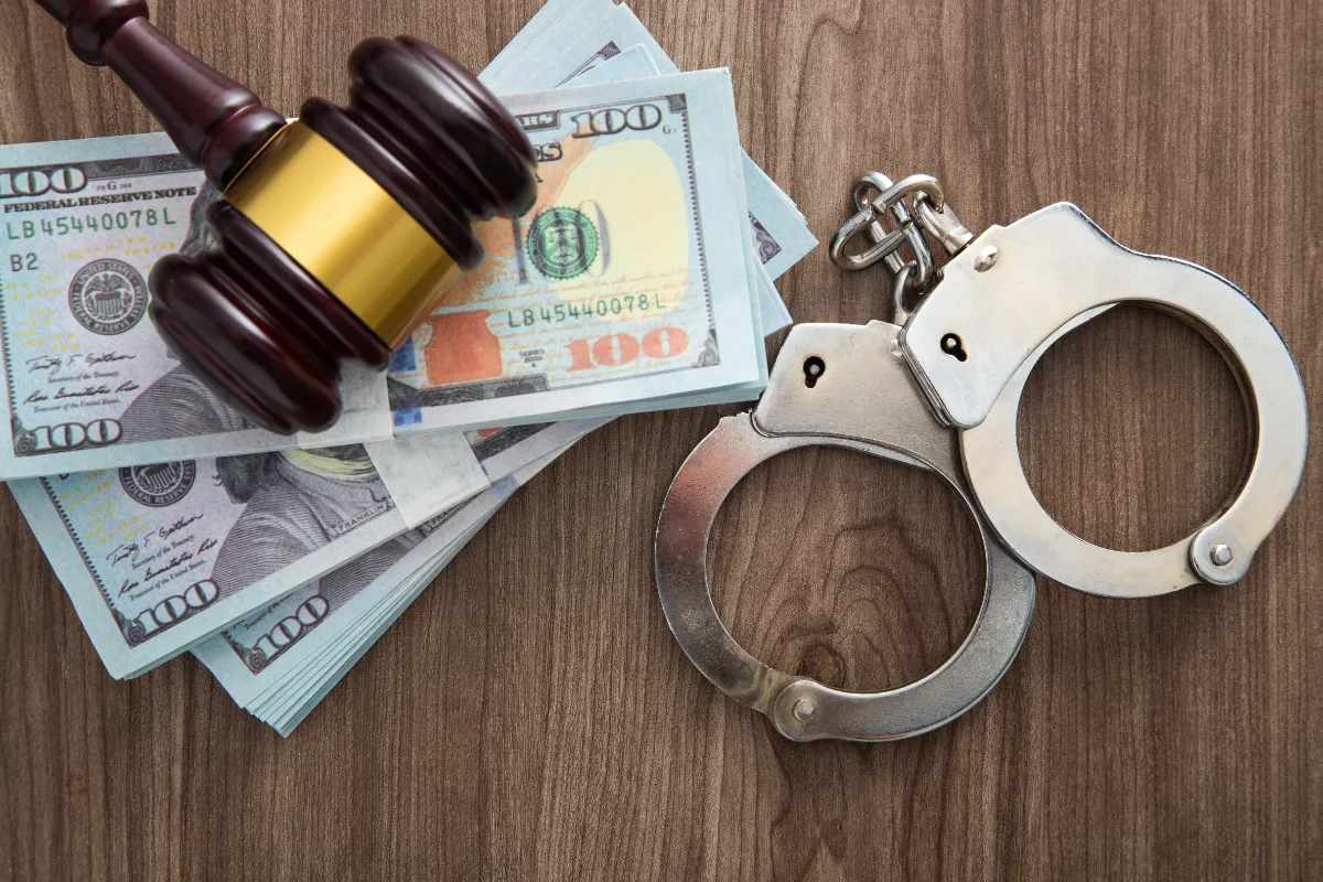 A wooden table displays both handcuffs and money, symbolizing charges and the need for a lawyer in a constitutional case.