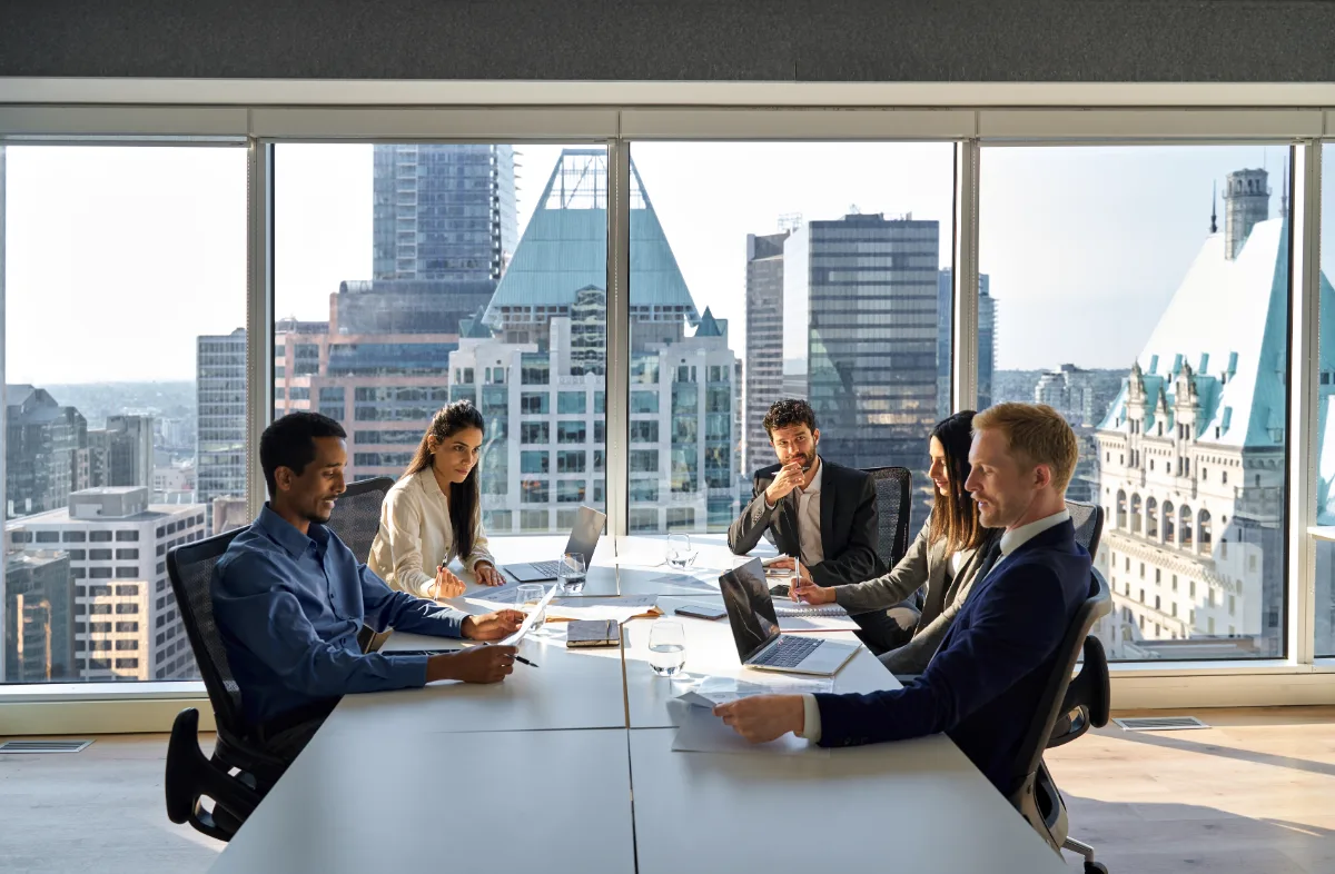 Professionals in a boardroom meeting with a city skyline view.
