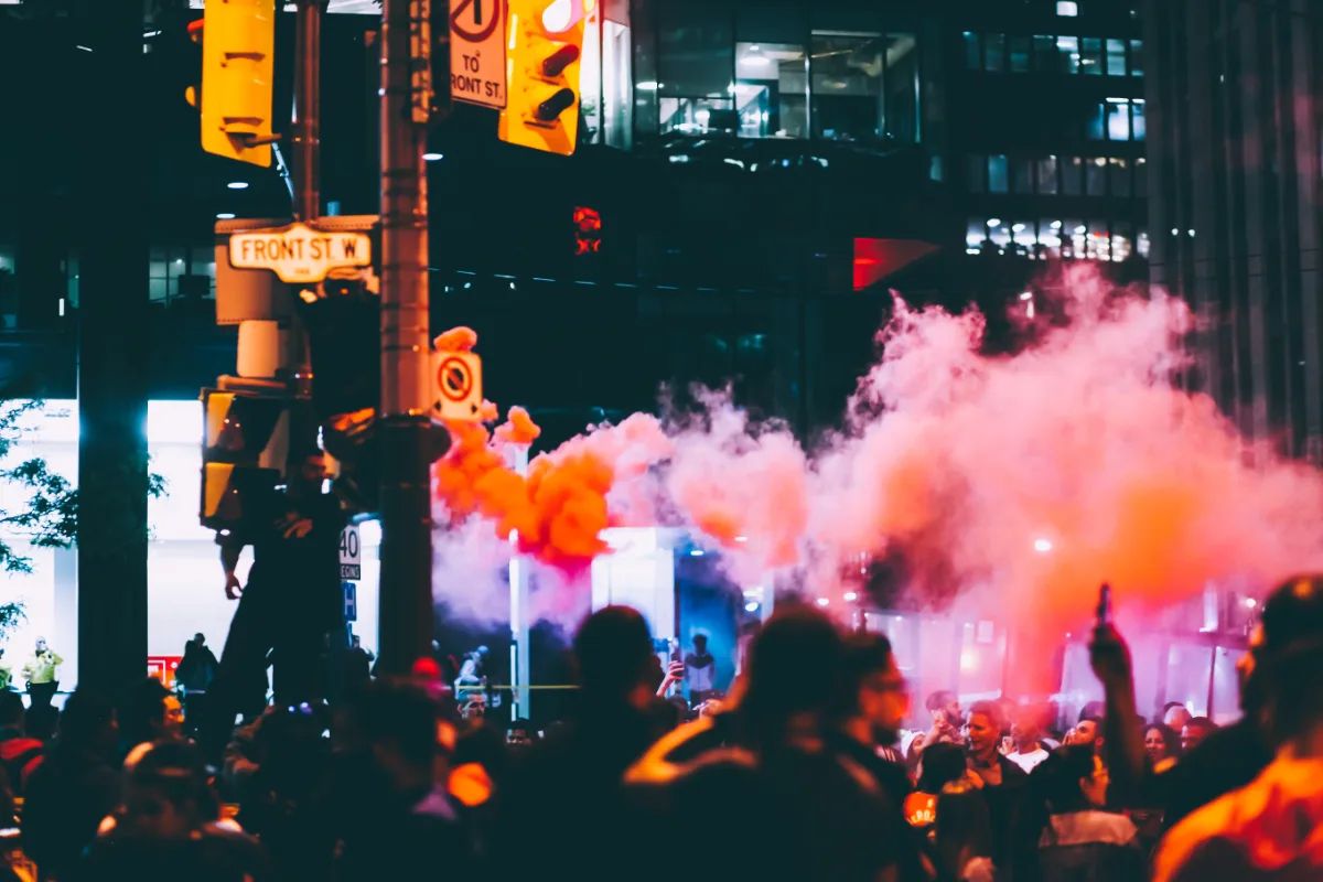 A crowd of people in a city at night with smoky atmosphere.