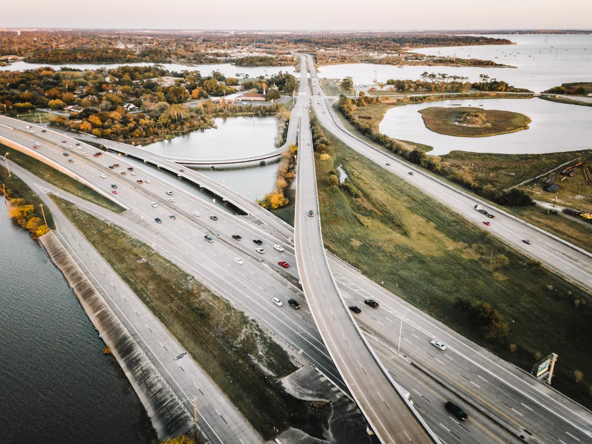 Aerial view of a multi-lane highway interchange in Texas with surrounding greenery and water bodies.