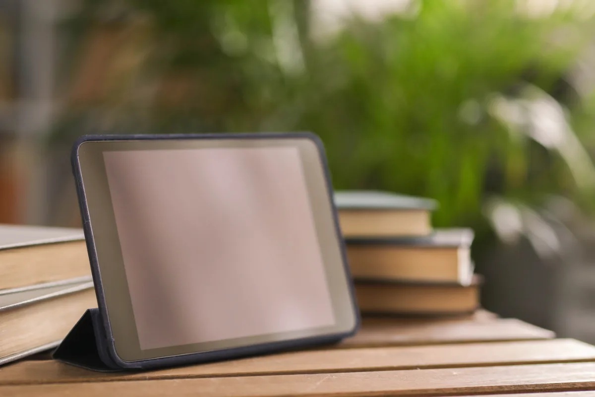A tablet pc on a wooden table with books in the background, perfect for any lawyer on probation.