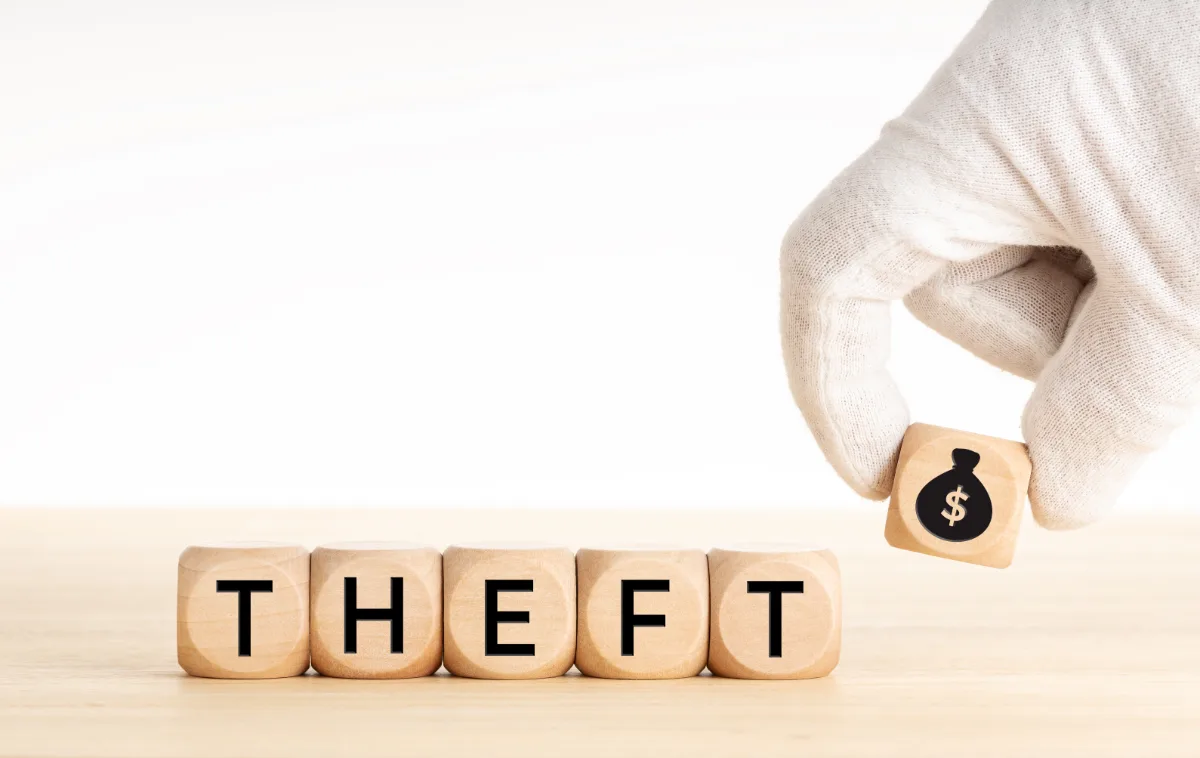 A hand holding a wooden block with the word theft on it, representing a potential misdemeanor offense for which legal representation from a lawyer may be necessary.