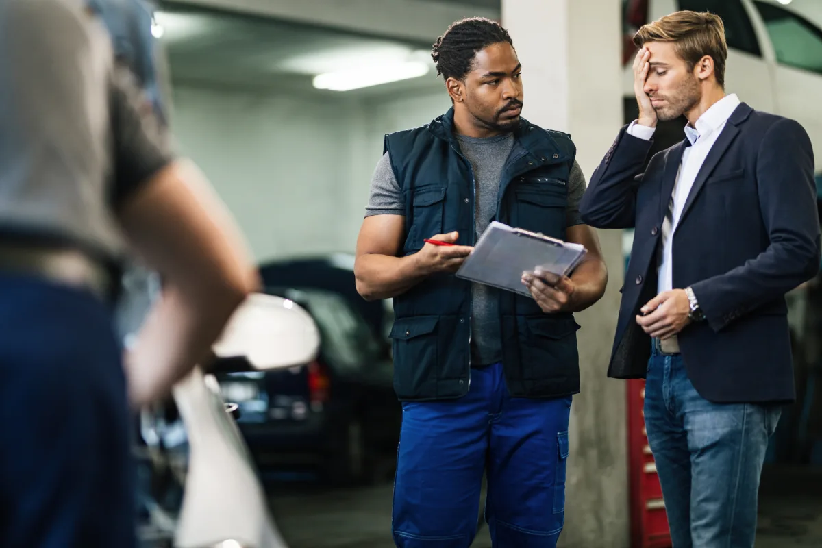 Mechanic discussing vehicle repairs with a car owner in a Texas parking garage.
