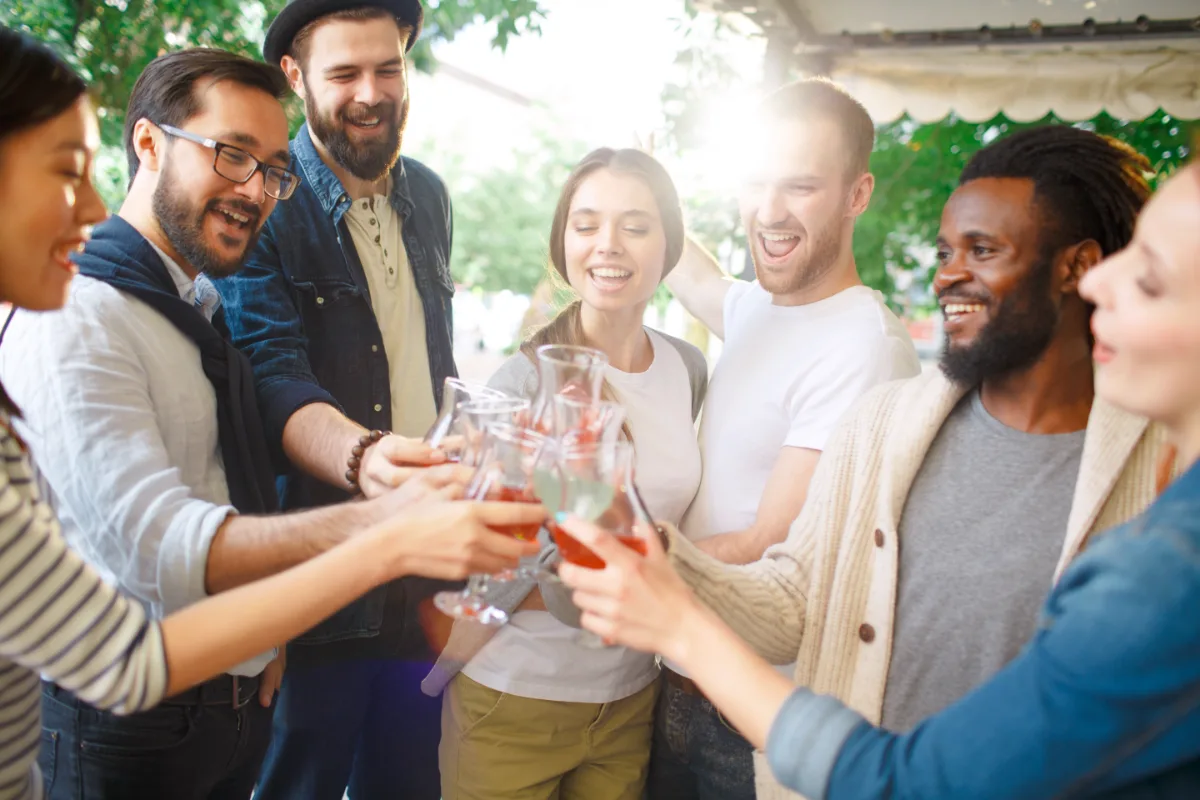 Group of friends toasting with drinks at an outdoor gathering.