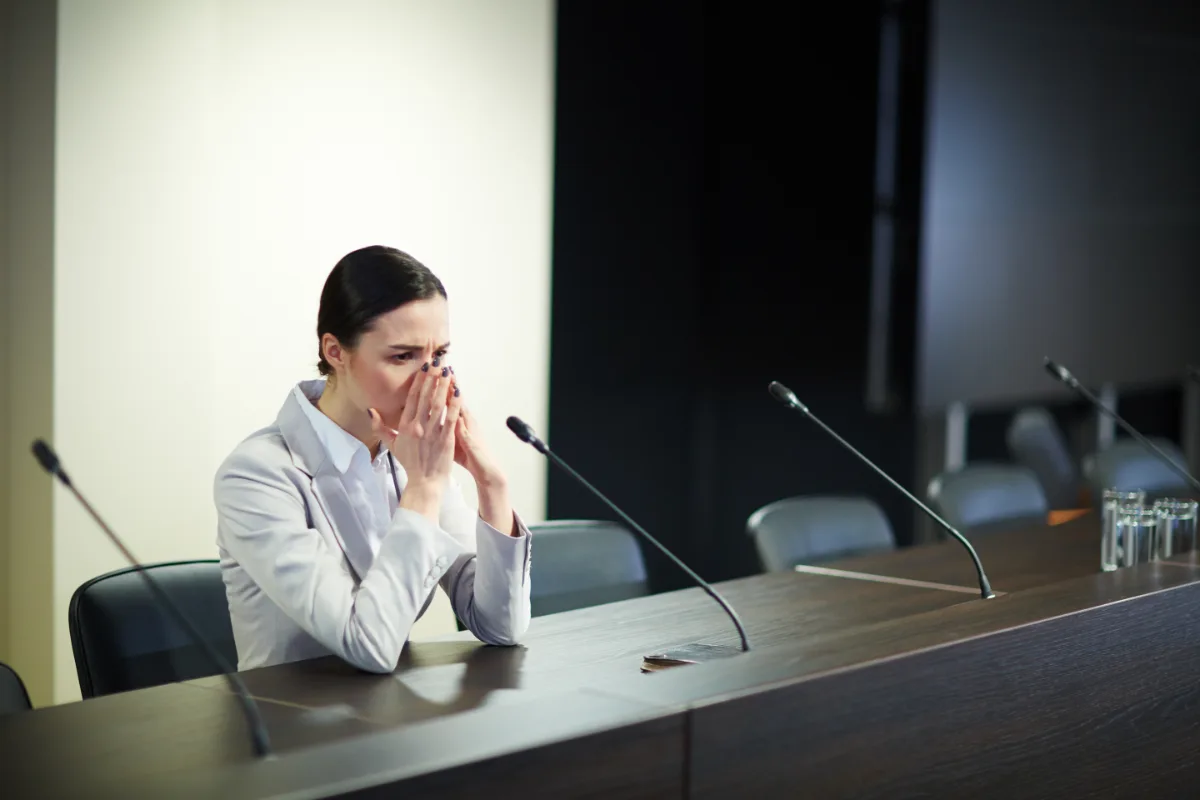 Woman speaking into microphones at a conference podium.