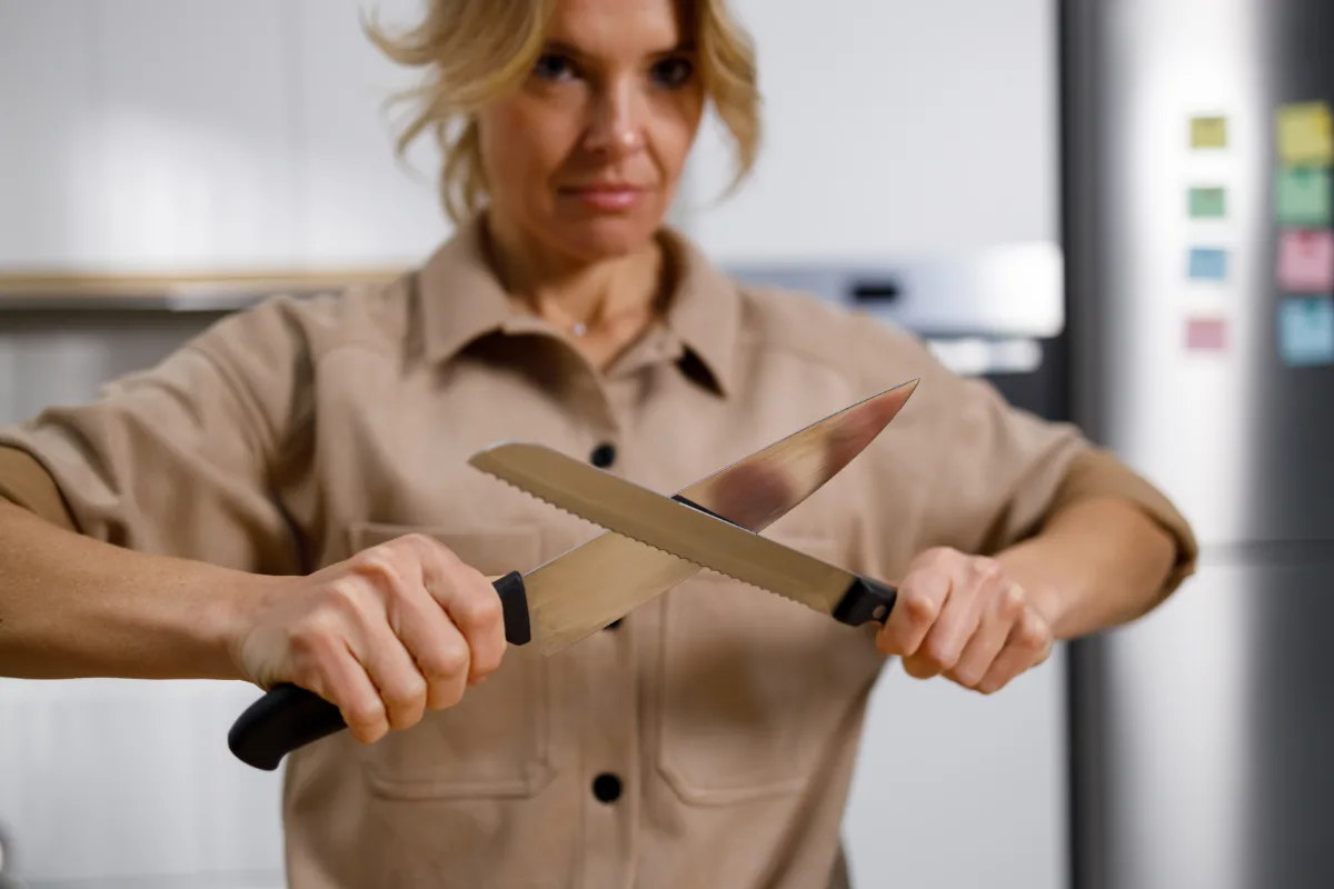 Woman sharpening a kitchen knife with a honing rod.